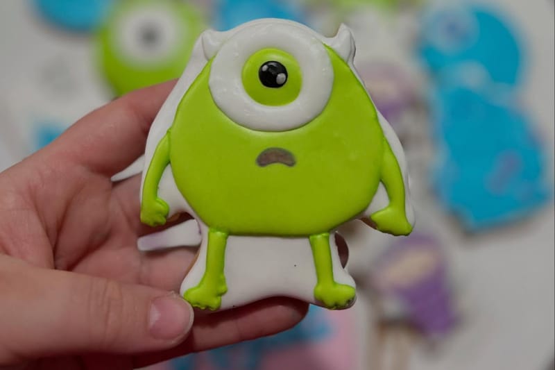 Biscoito decorado em formato de personagem, segurado na mão, com o relevo do glacê real bem visível