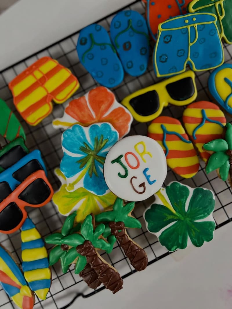 Biscoitos decorados com tema tropical: chinelo, óculos de sol, flores e o nome Jorge em letras coloridas